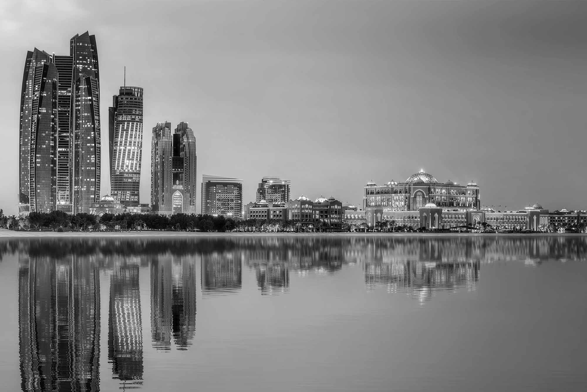 A stunning black-and-white view of Abu Dhabi's skyline reflecting on calm waters, showcasing architectural elegance and serenity.