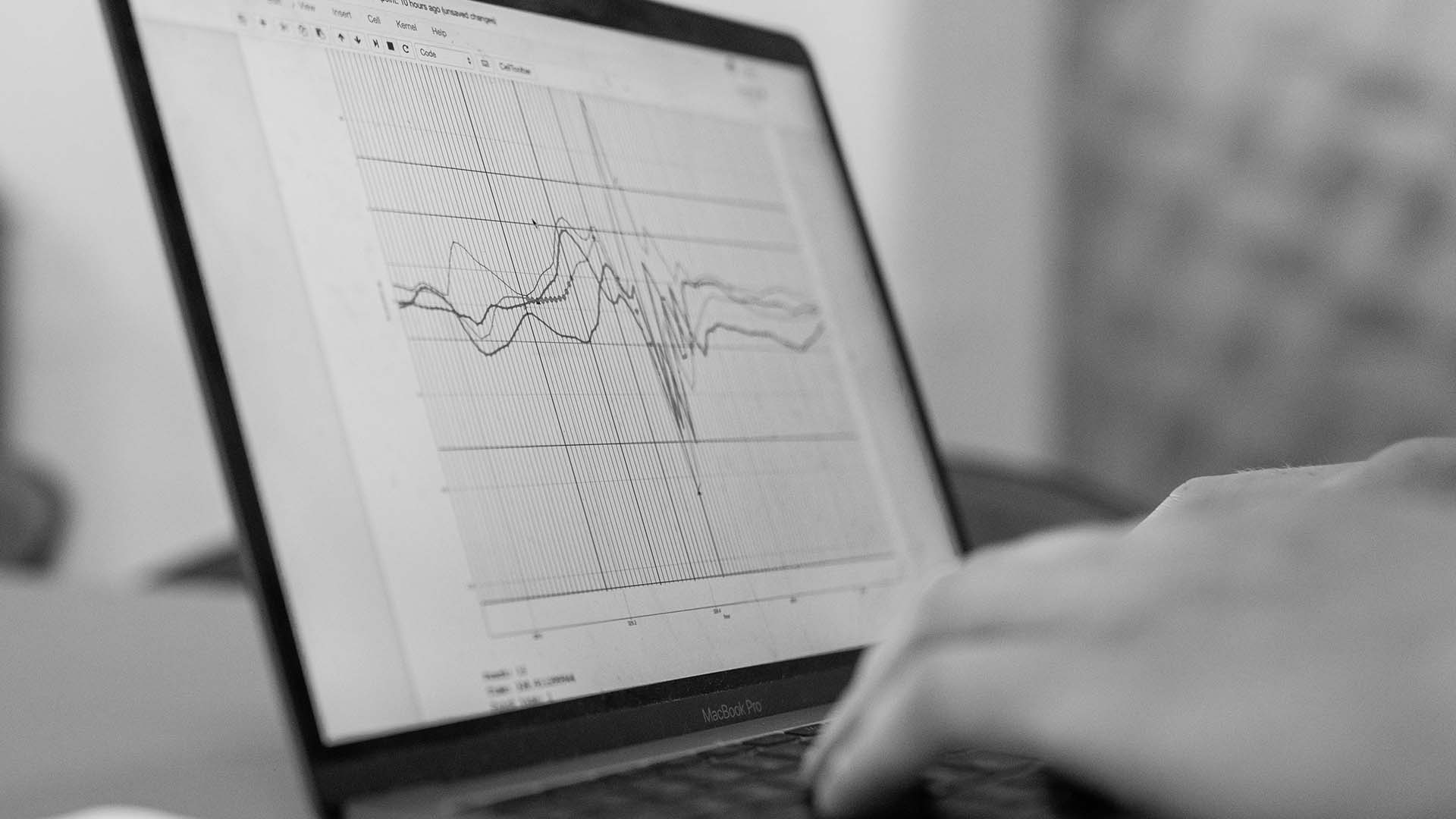 Analyzing complex data graphs on a MacBook Pro, showcasing focus and precision in data-driven decision-making.